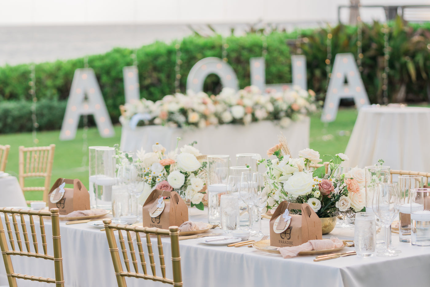 Outdoor ocean front wedding with chrsyalis box at each seat as wedding favor in front of a Aloha sign in Ko Olina, Kapolei, Hawaii