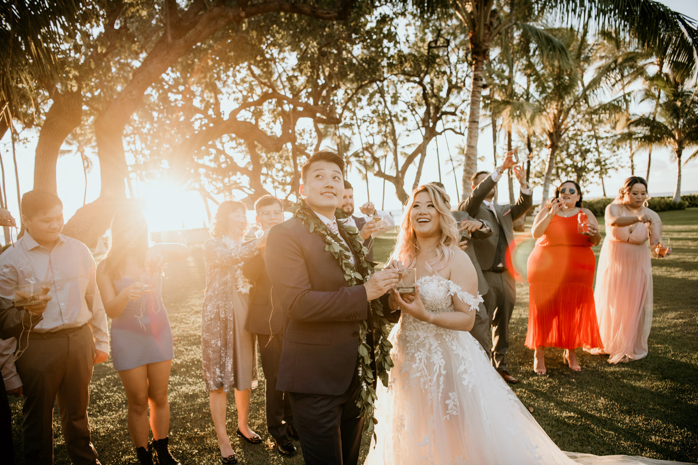 Wedding couple and the wedding party opening up the clear box to release monarch butterflies in hawaii at an outdoor ocean front forest venue 