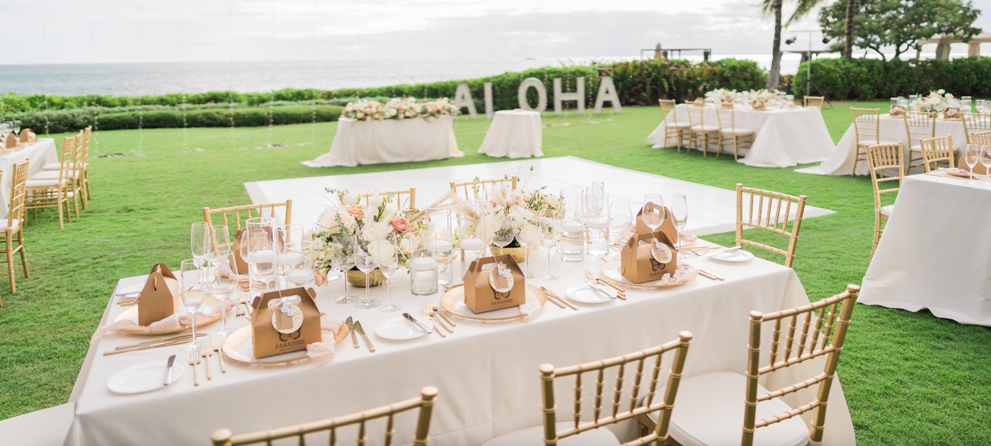 Dinner reception at a outdoor ocean front venue in hawaii with chrysalis boxes as wedding favors placed at each seat 